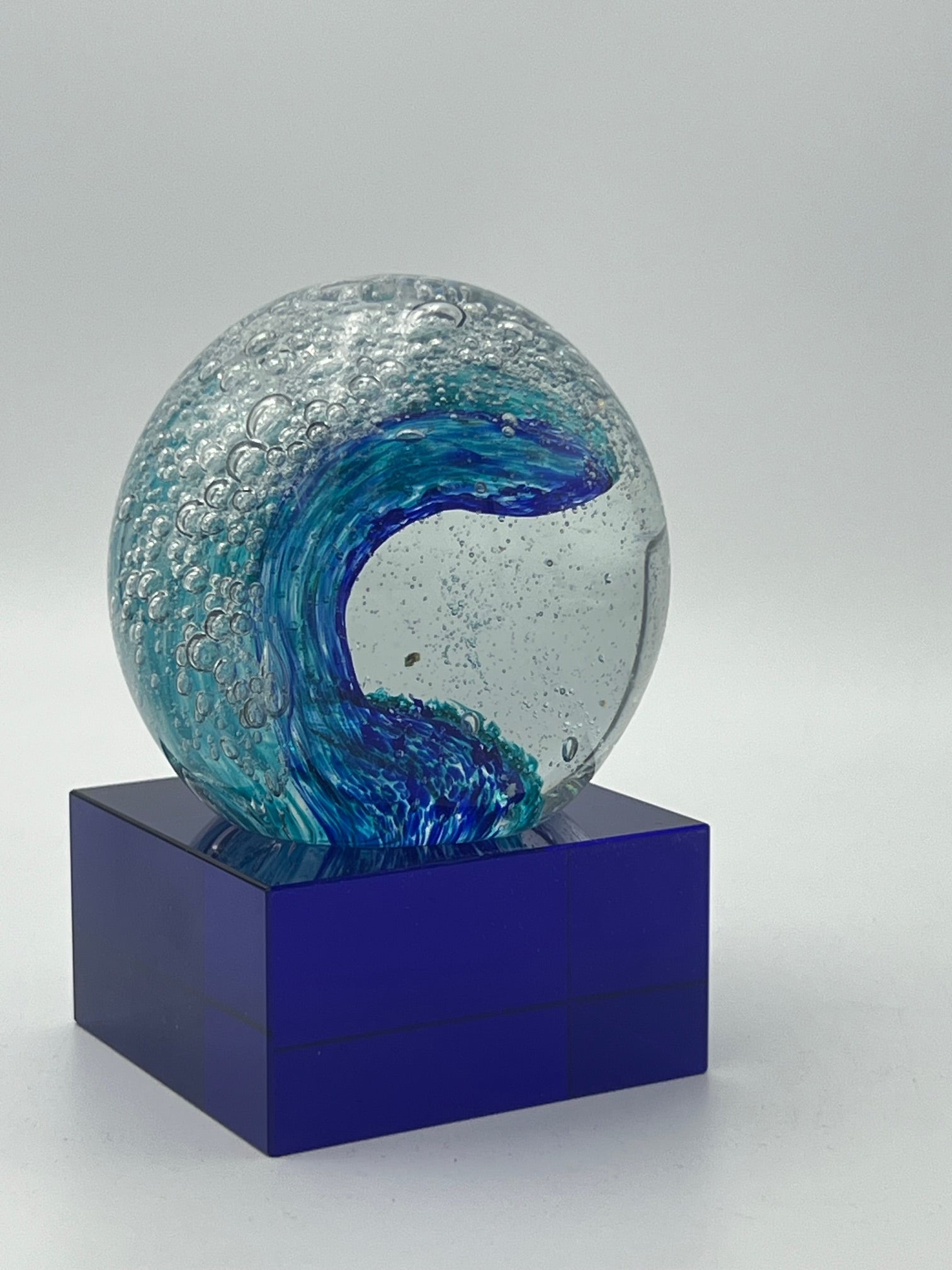 Clear globe with crashing wave inside on blue glass base