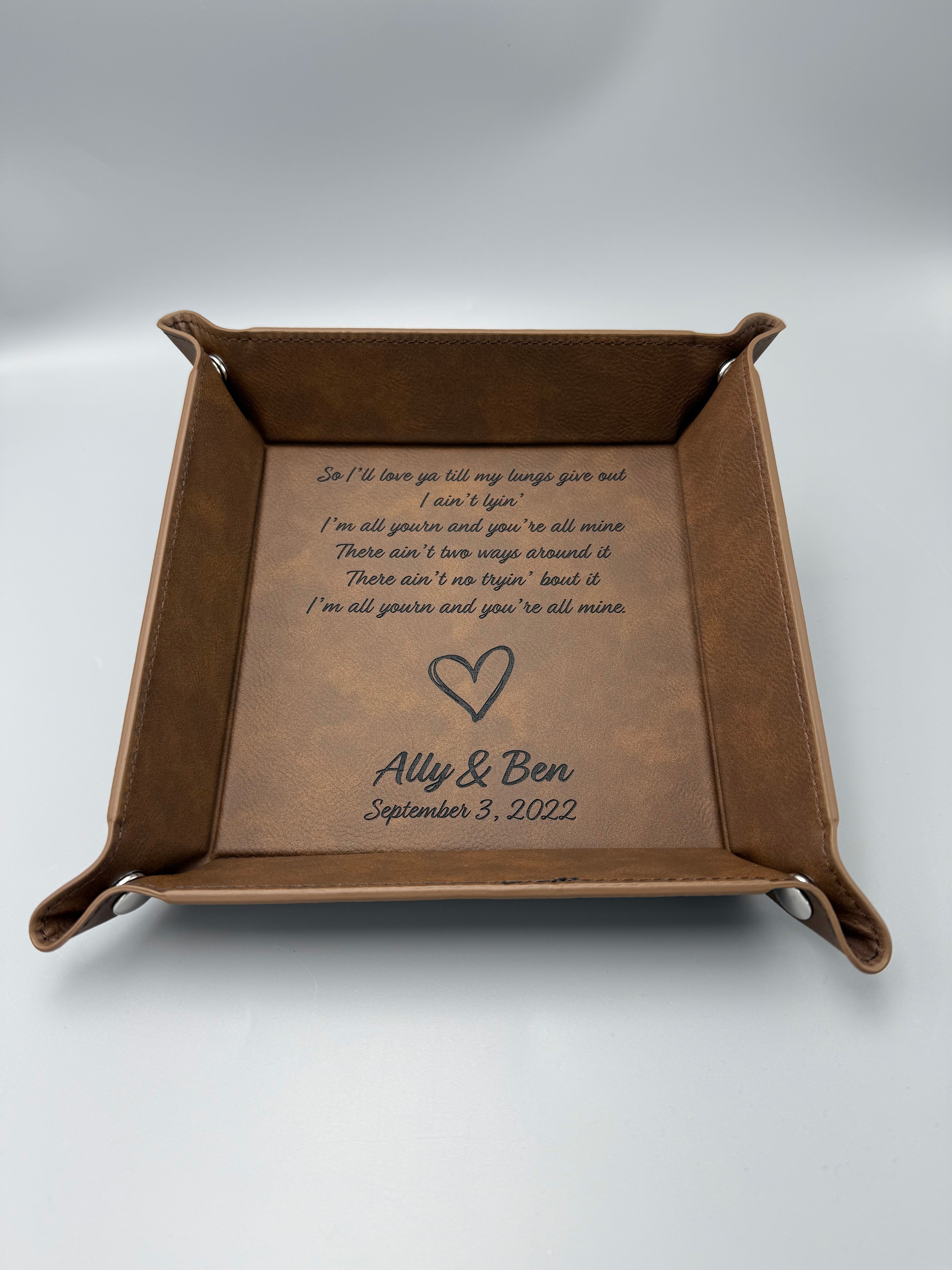 Brown leather tray with engraved text and heart design on a white background