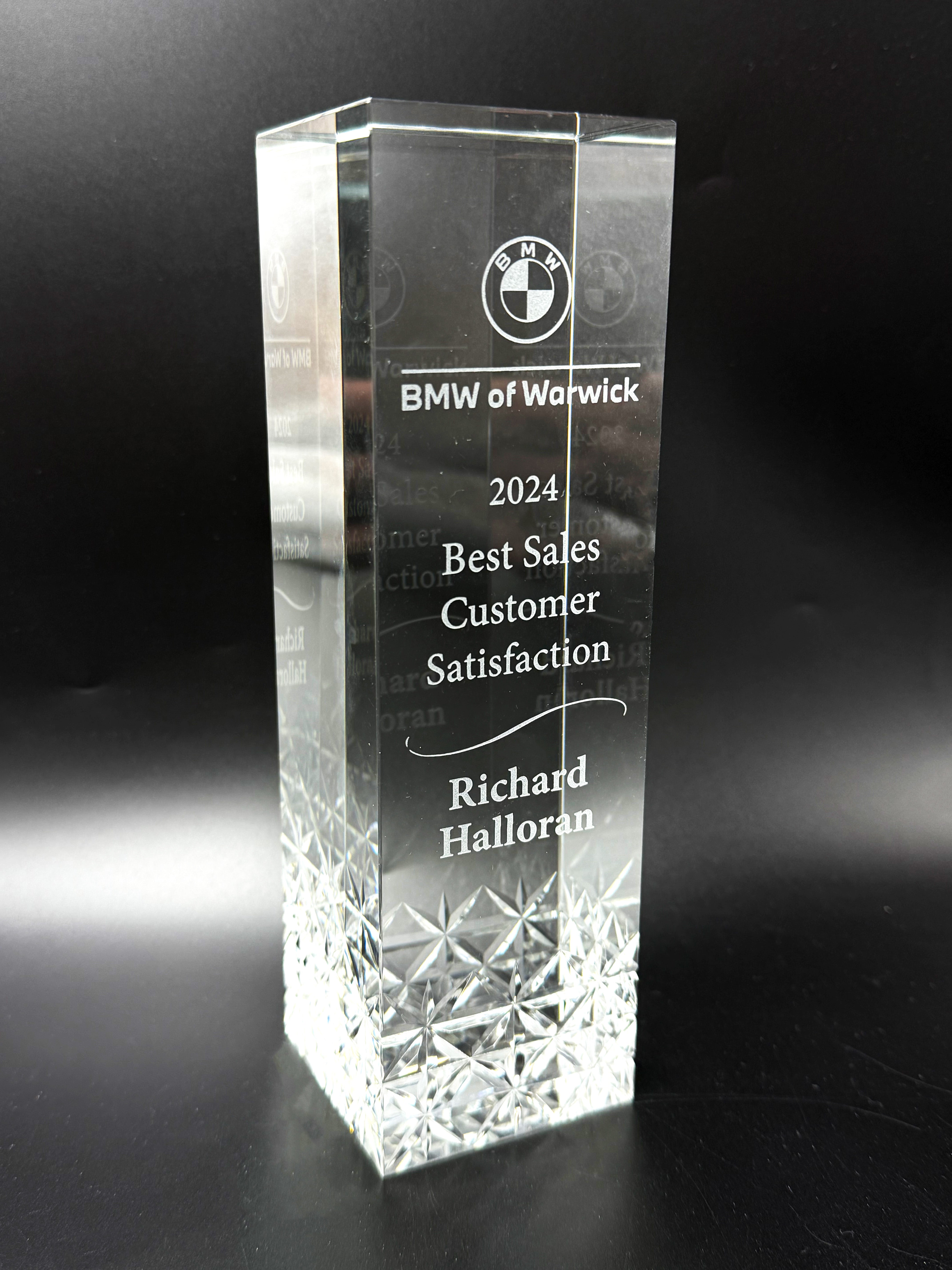 Crystal award with engraved text and BMW logo on a black background
