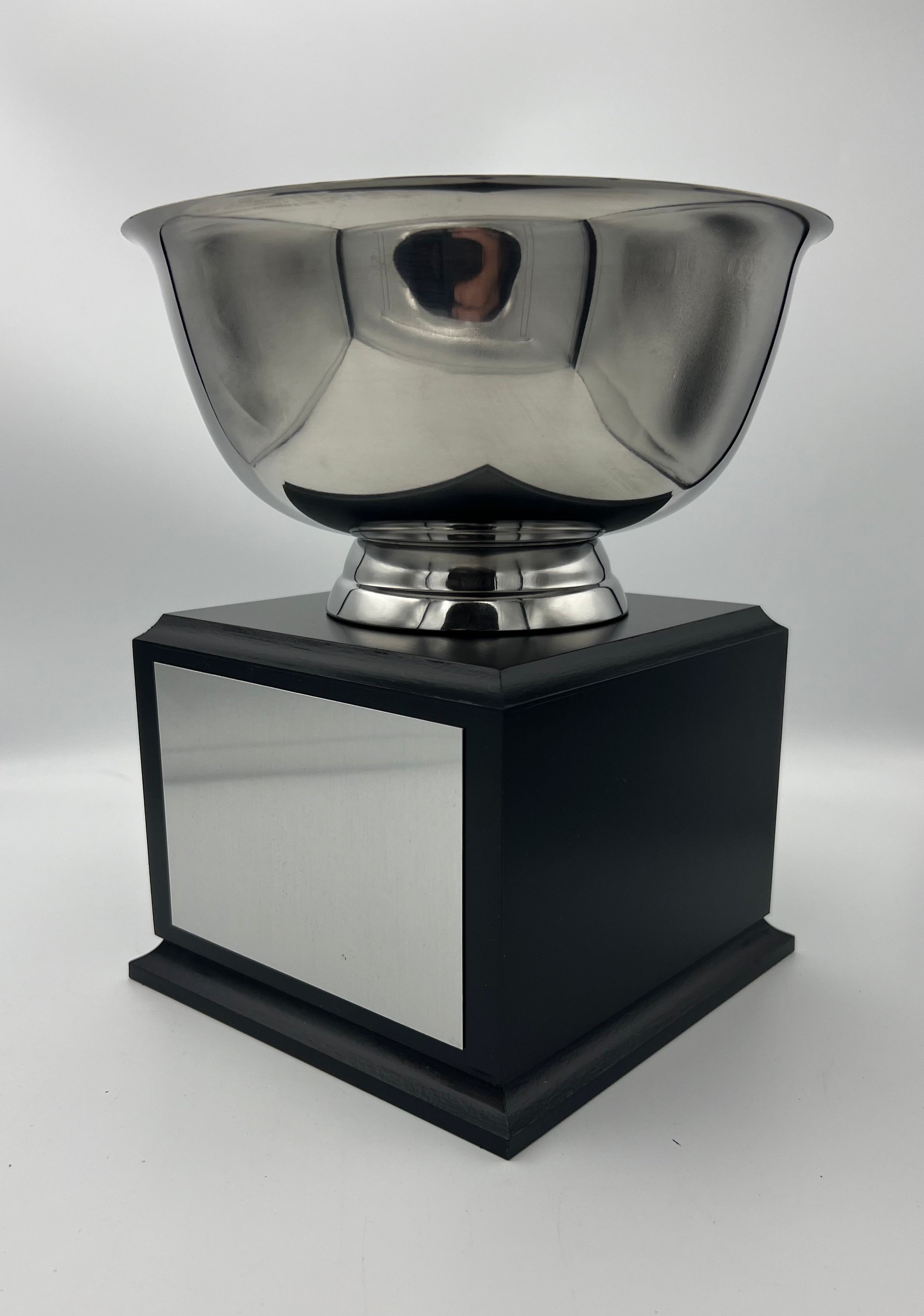 Bright nickel plated metal bowl mounted on a black wood base