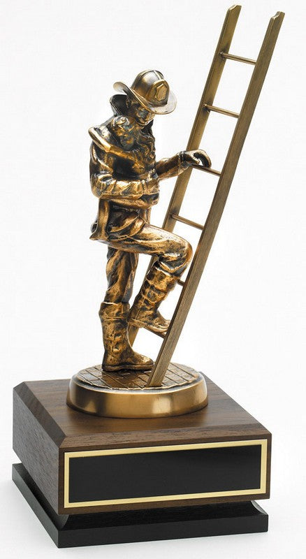 Statue of a firefighter climbing a ladder on a wooden base with a black plaque.