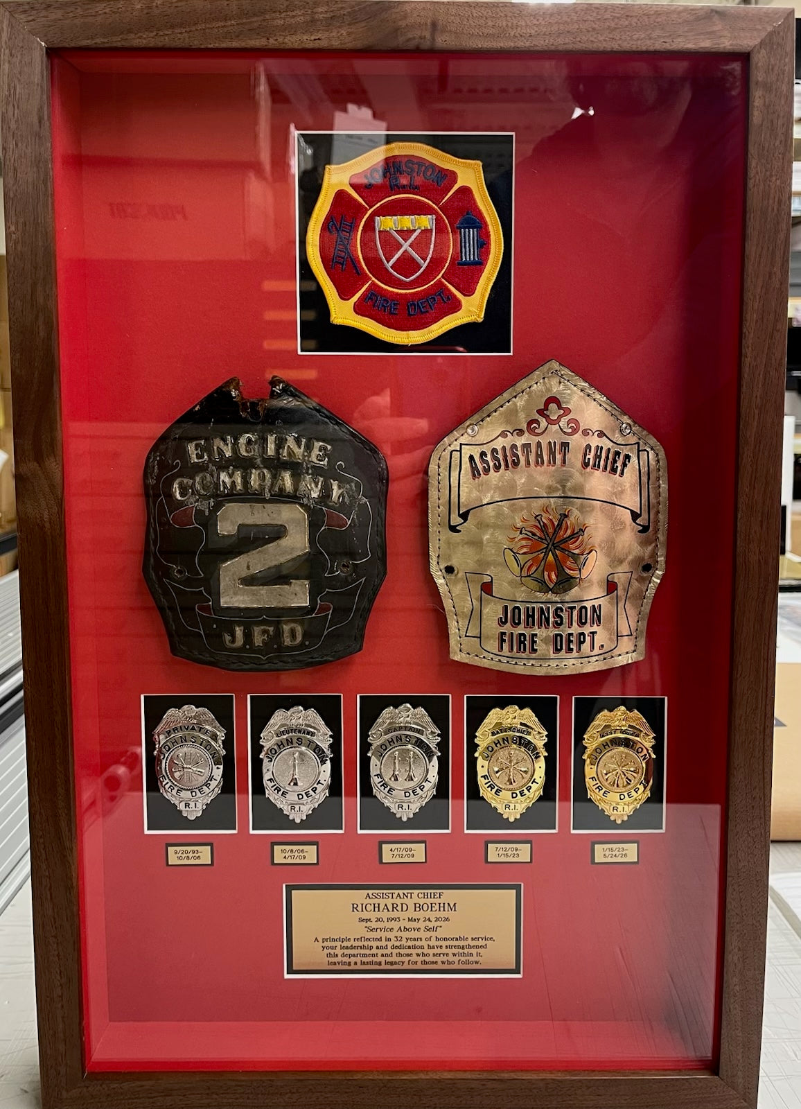 Framed display of firefighter badges and insignias on a red background