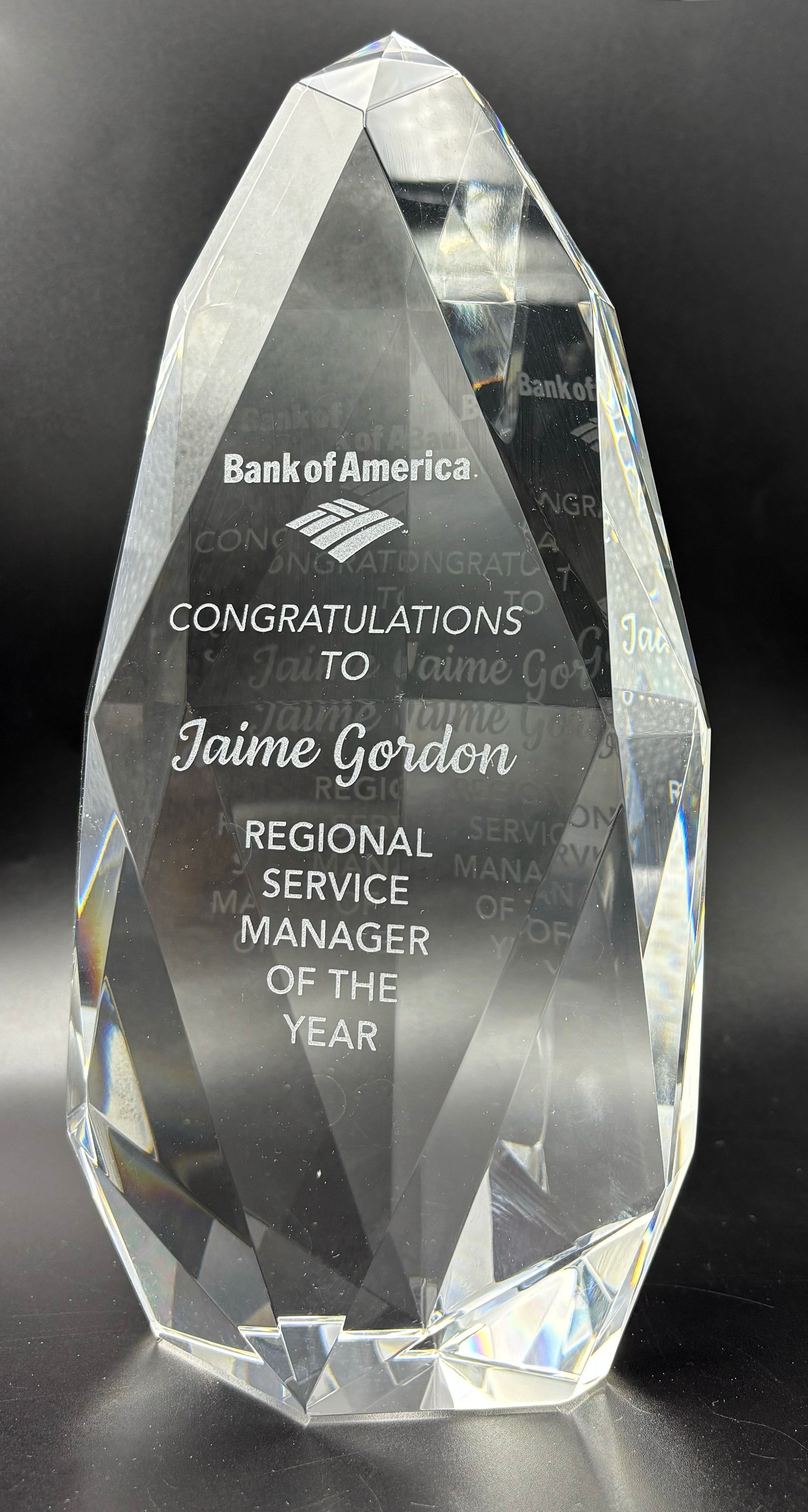 Multi-faceted crystal award with engraved text on a front